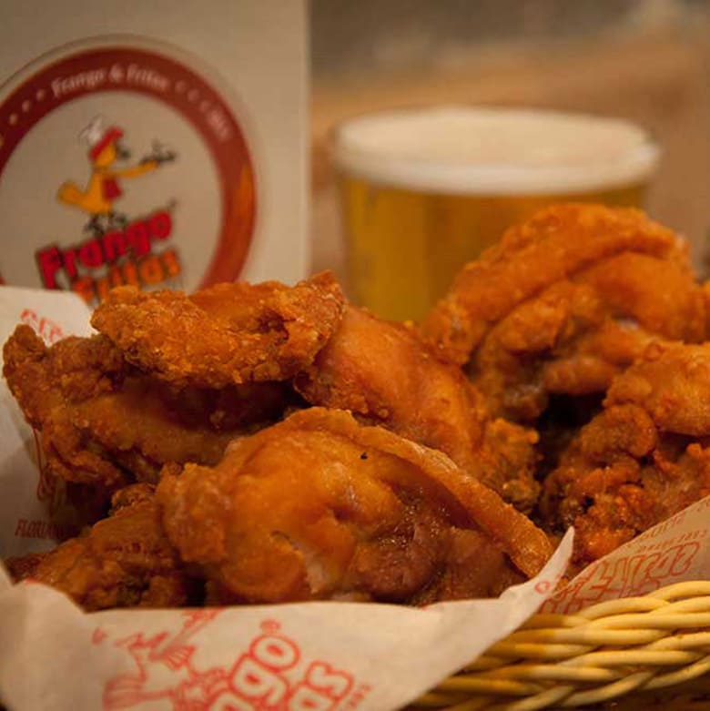 Porção de frango crocante do Frango & Fritas com cerveja ao fundo